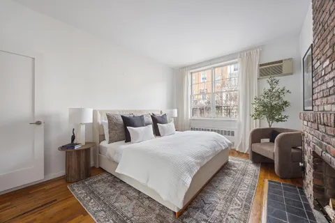 a bedroom with a bed a couch and wooden floor