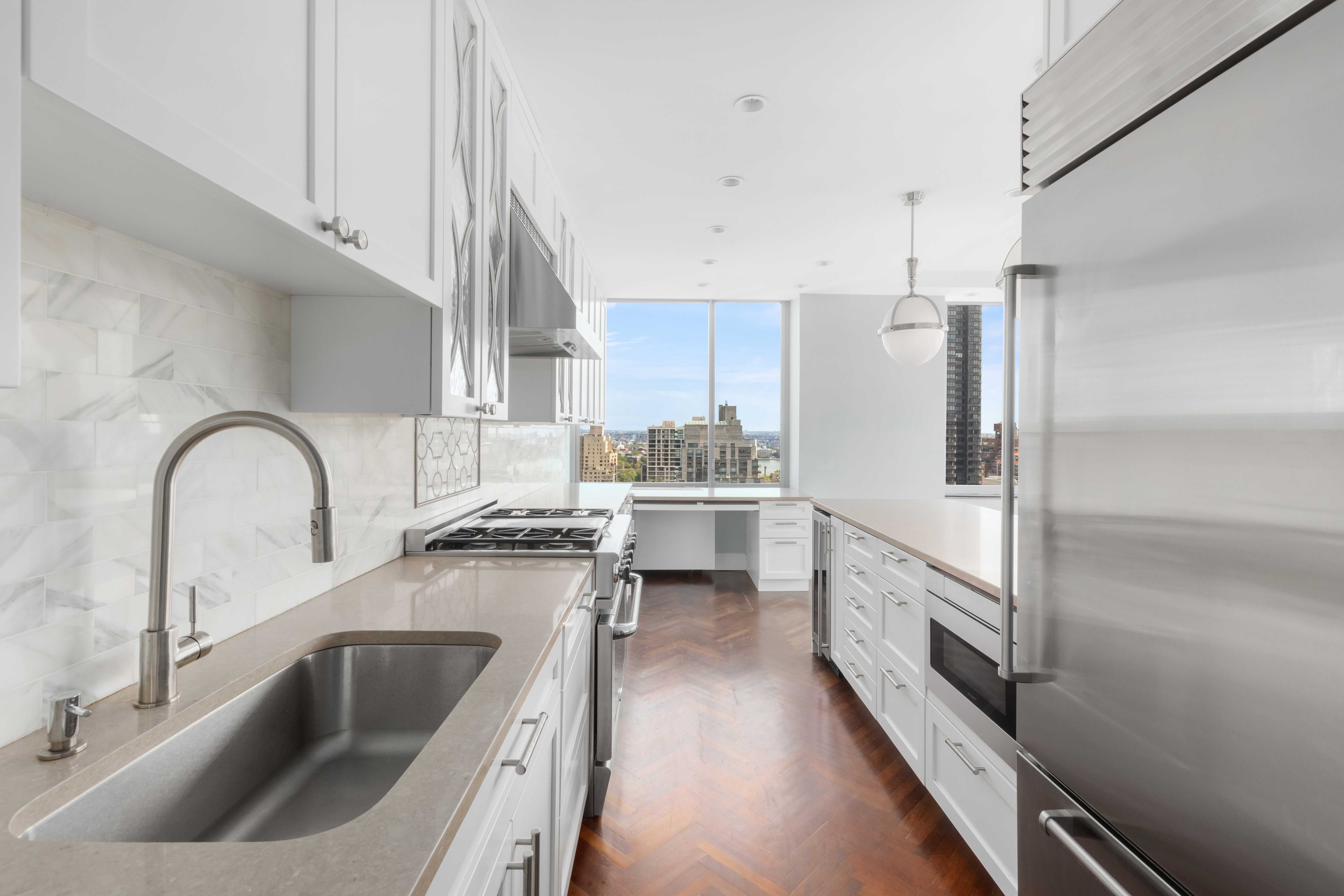 360 East 88th Street, Unit 20D Manhattan, NY 10128 - Photo 3 of 15 a kitchen with stainless steel appliances a sink a stove and a refrigerator with wooden floor