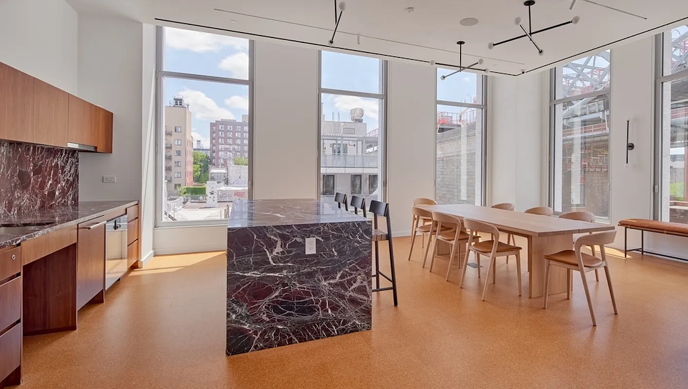 5 South 5th Street, Unit PH2B Brooklyn, NY 11249 - Photo 26 of 27 a large white kitchen with granite countertop a stove a sink a dining table and chairs