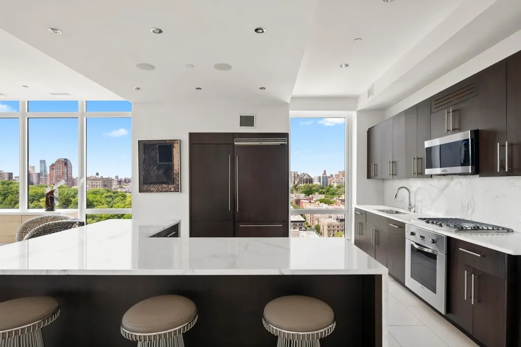 a kitchen with stainless steel appliances a sink a stove a microwave a center island and cabinets