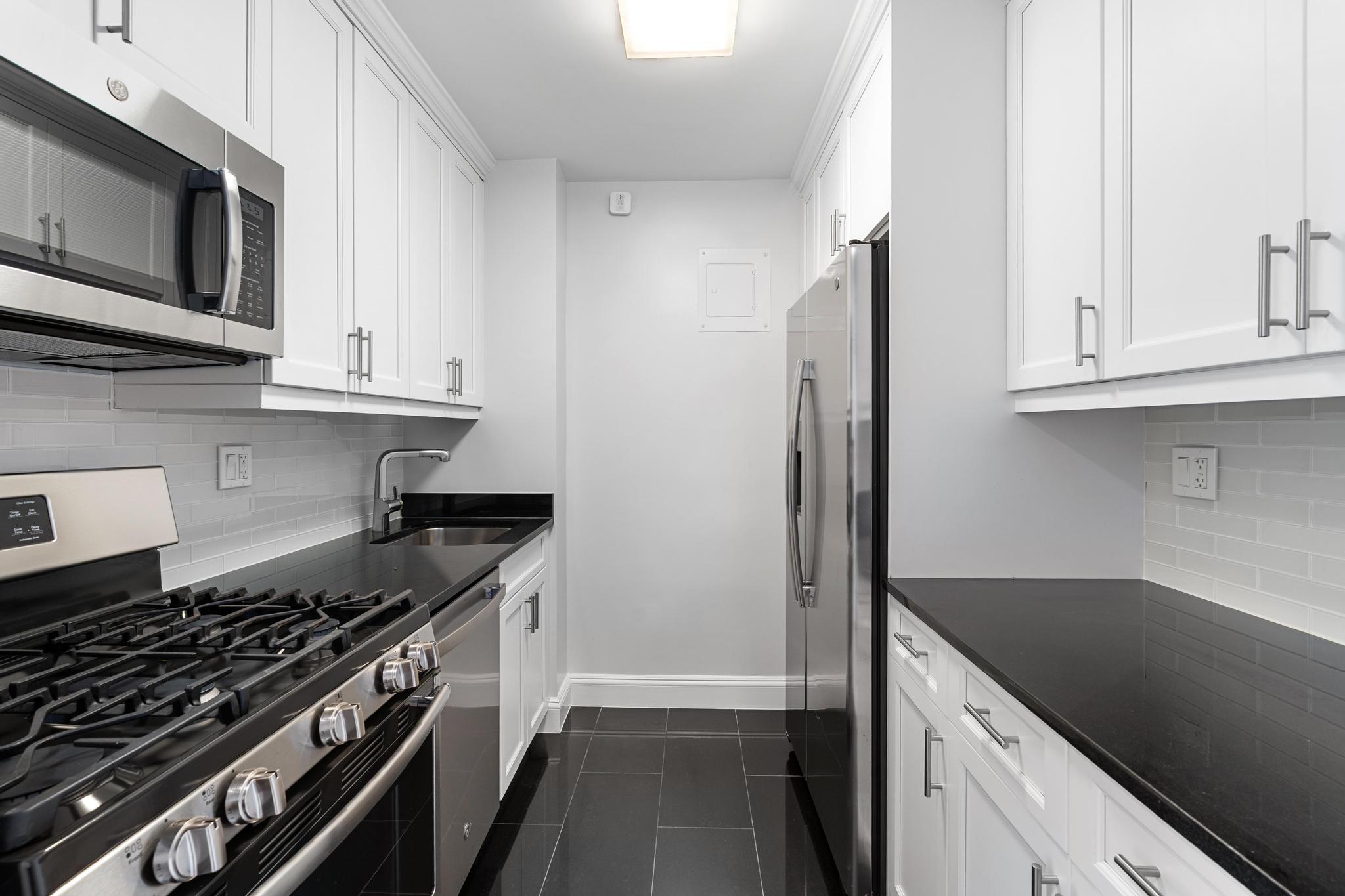 155 West 68th Street, Unit 1027 Manhattan, NY 10023 - Photo 4 of 8 a kitchen with stainless steel appliances granite countertop a stove and a refrigerator