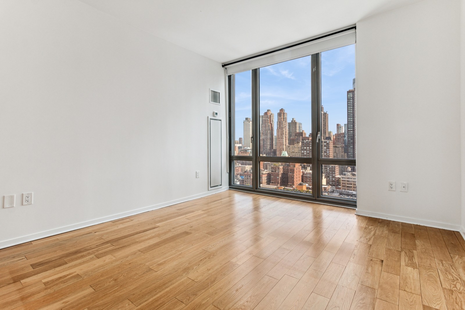 310 West 52nd Street, Unit 22H Manhattan, NY 10019 - Photo 7 of 12 a view of a big room with wooden floor and a floor to ceiling window