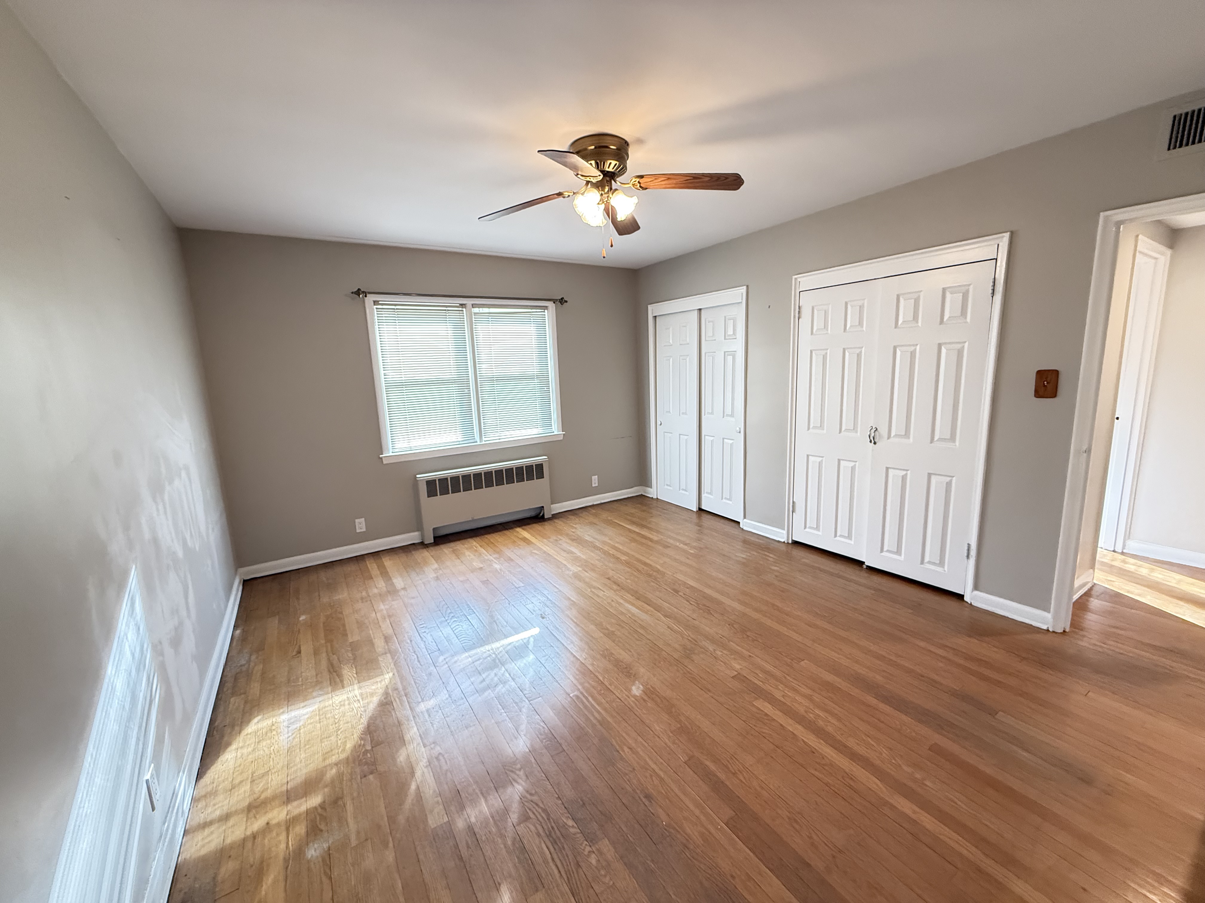 3236 Country Club Road Bronx, NY 10465 - Photo 9 of 22 an empty room with wooden floor chandelier fan and windows