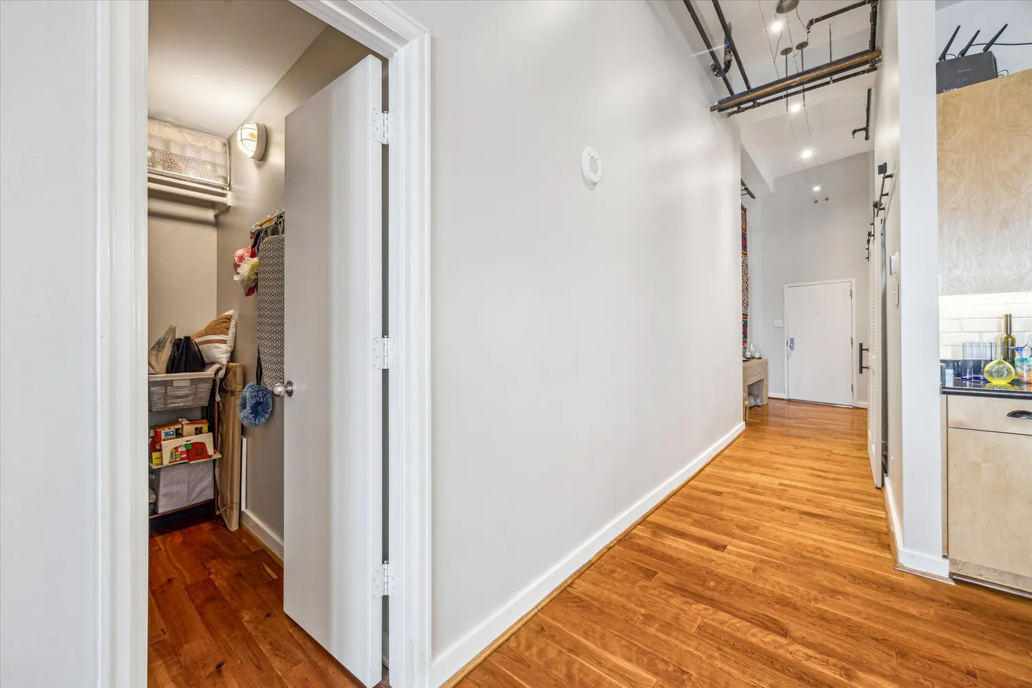 a view of a hallway with wooden floor and a bathroom