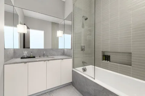 a bathroom with a granite countertop sink a mirror a bathtub and shower