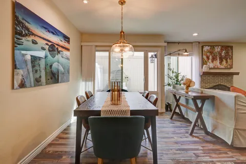 a dining room with wooden floor a chandelier a wooden table and chairs