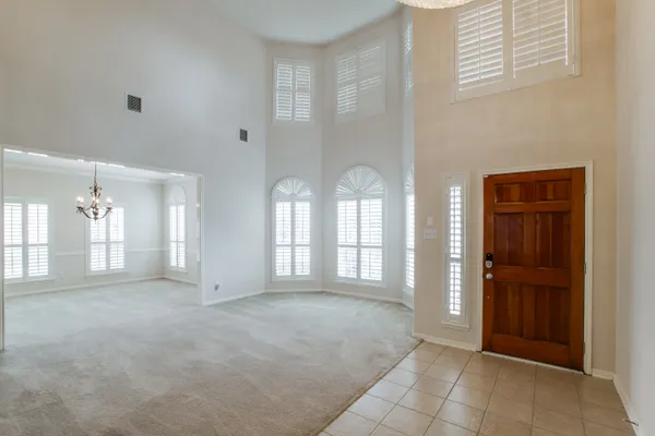 an empty room with chandelier fan and windows