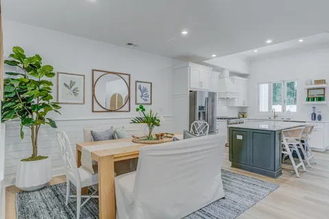 a kitchen with stainless steel appliances kitchen island granite countertop a stove a sink a dining table and chairs