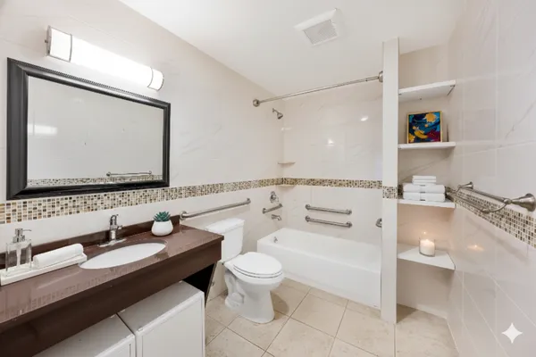 a bathroom with a granite countertop sink a toilet a mirror and bathtub