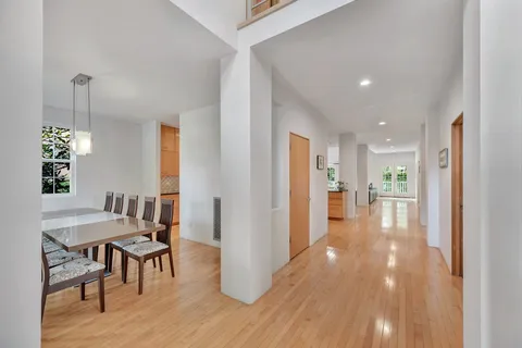 a kitchen with stainless steel appliances granite countertop a stove a refrigerator a sink a dining table and chairs with wooden floor