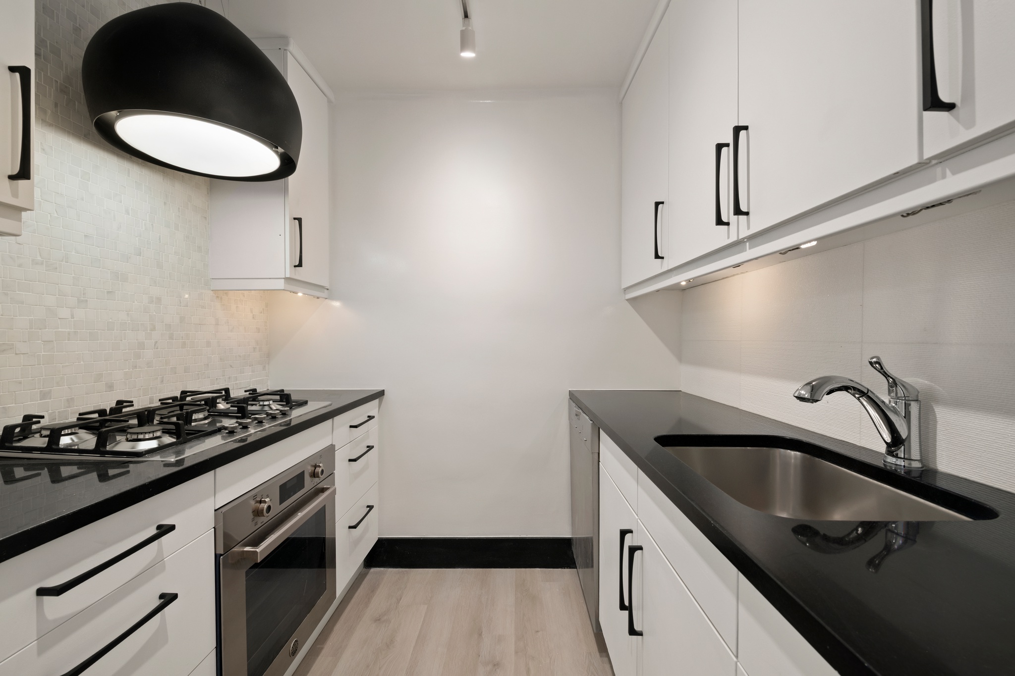 155 West 68th Street, Unit 1410 Manhattan, NY 10023 - Photo 5 of 11 a kitchen with stainless steel appliances a sink stove and cabinets