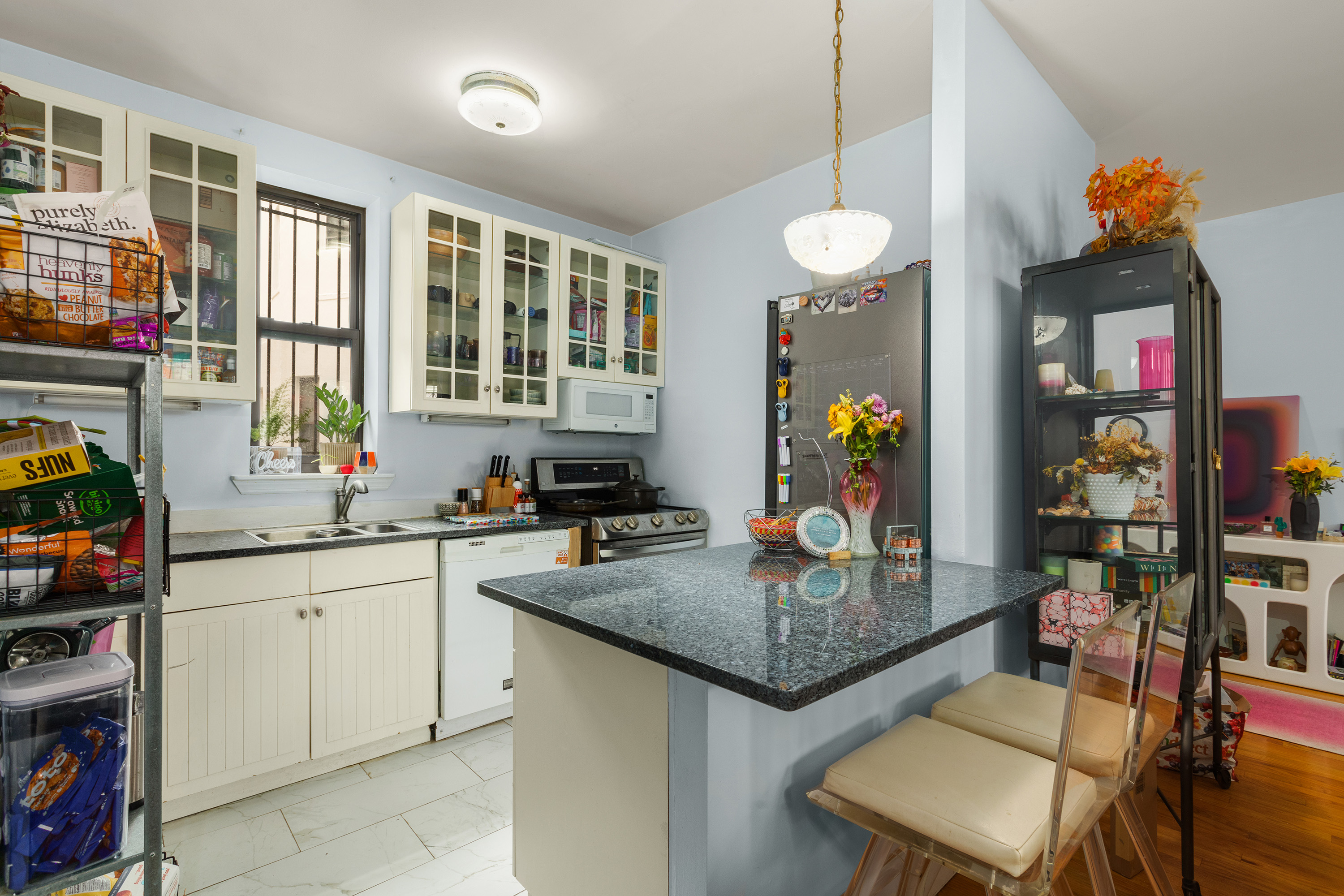 502 West 141st Street, Unit 1A Manhattan, NY 10031 - Photo 2 of 8 a kitchen with stainless steel appliances granite countertop a stove a sink and a dining table with chairs