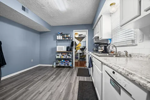 a kitchen with granite countertop a sink wooden floor and stainless steel appliances