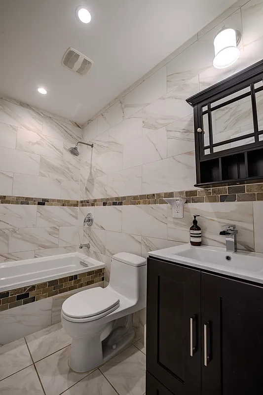 877 Greene Avenue, Unit 2 Brooklyn, NY 11221 - Photo 4 of 13 a bathroom with a toilet a sink and a mirror