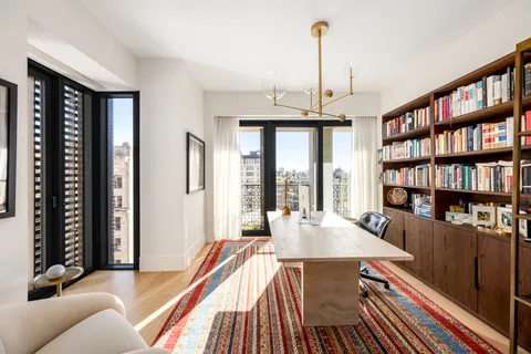 a living room with furniture a bookshelf and a large window