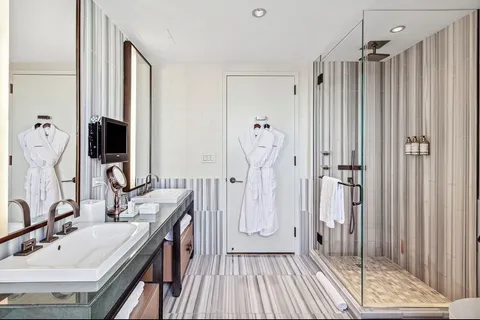 a bathroom with double vanity sink a mirror a glass door a shower and a mirror