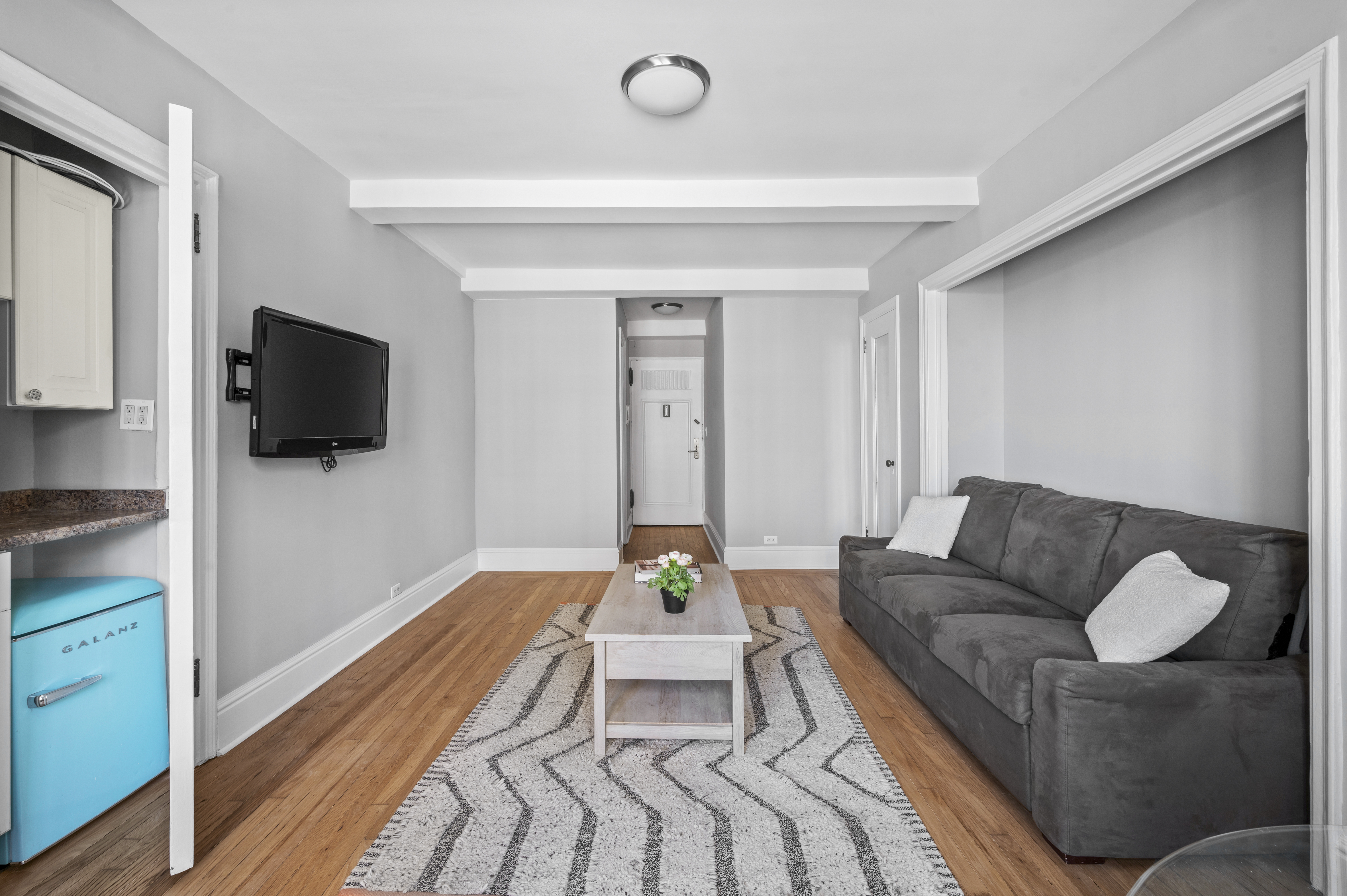 25 Tudor City Place, Unit 303 Manhattan, NY 10017 - Photo 3 of 6 a living room with furniture and a flat screen tv