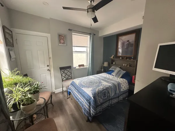 a bedroom with a bed table chair and a window