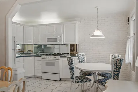 a kitchen with stainless steel appliances granite countertop a stove a sink a microwave a refrigerator a dining table and chairs with wooden floor