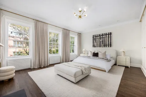 a bedroom with a large bed couch and windows