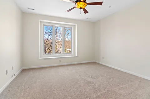an empty room with windows and chandelier fan