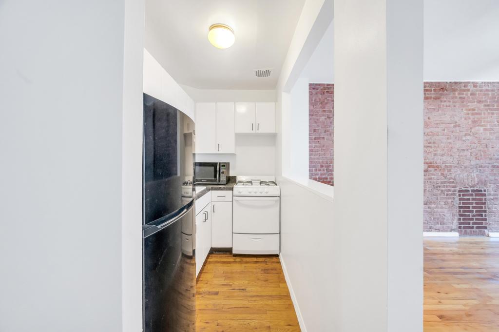 344 West 49th Street, Unit 4B Manhattan, NY 10019 - Photo 3 of 11 a kitchen with a refrigerator and a stove