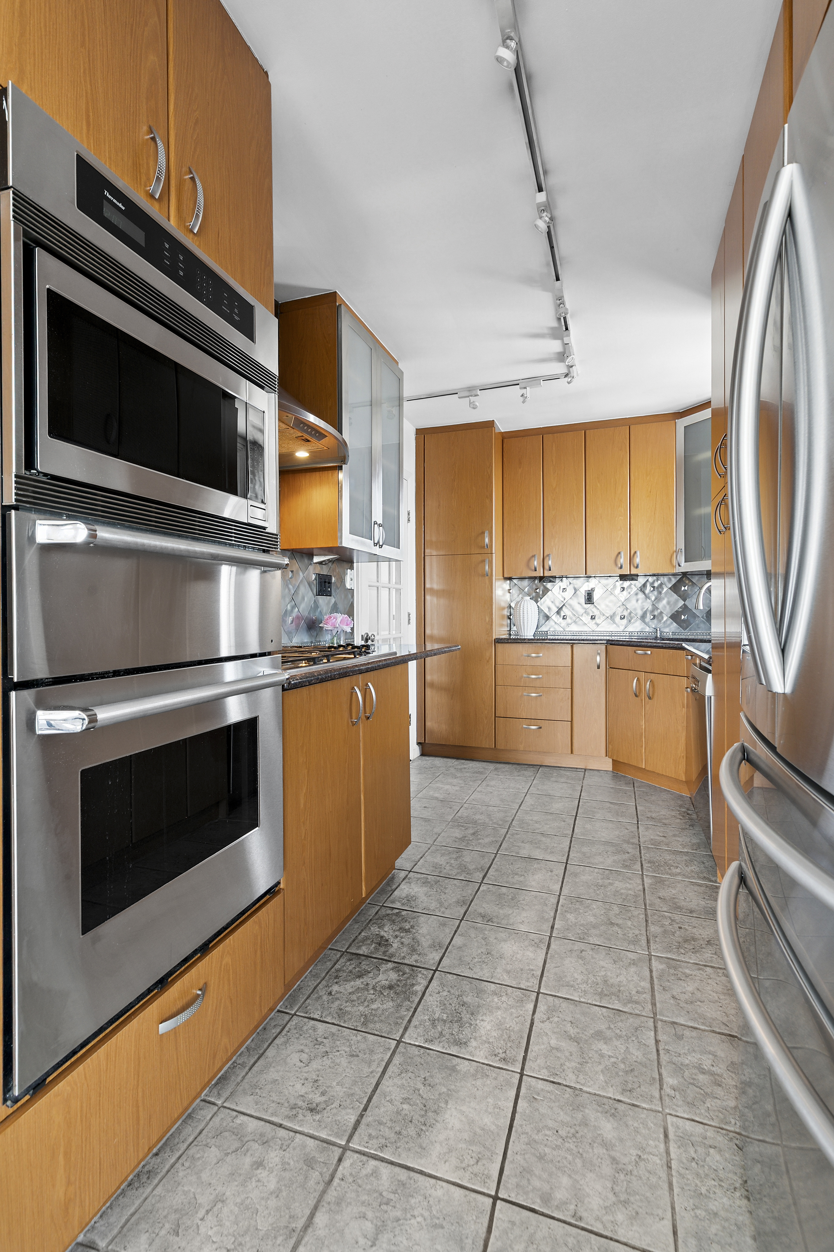 200 East 89th Street, Unit 34CD Manhattan, NY 10128 - Photo 6 of 20 a kitchen with stainless steel appliances granite countertop a stove a microwave and a sink