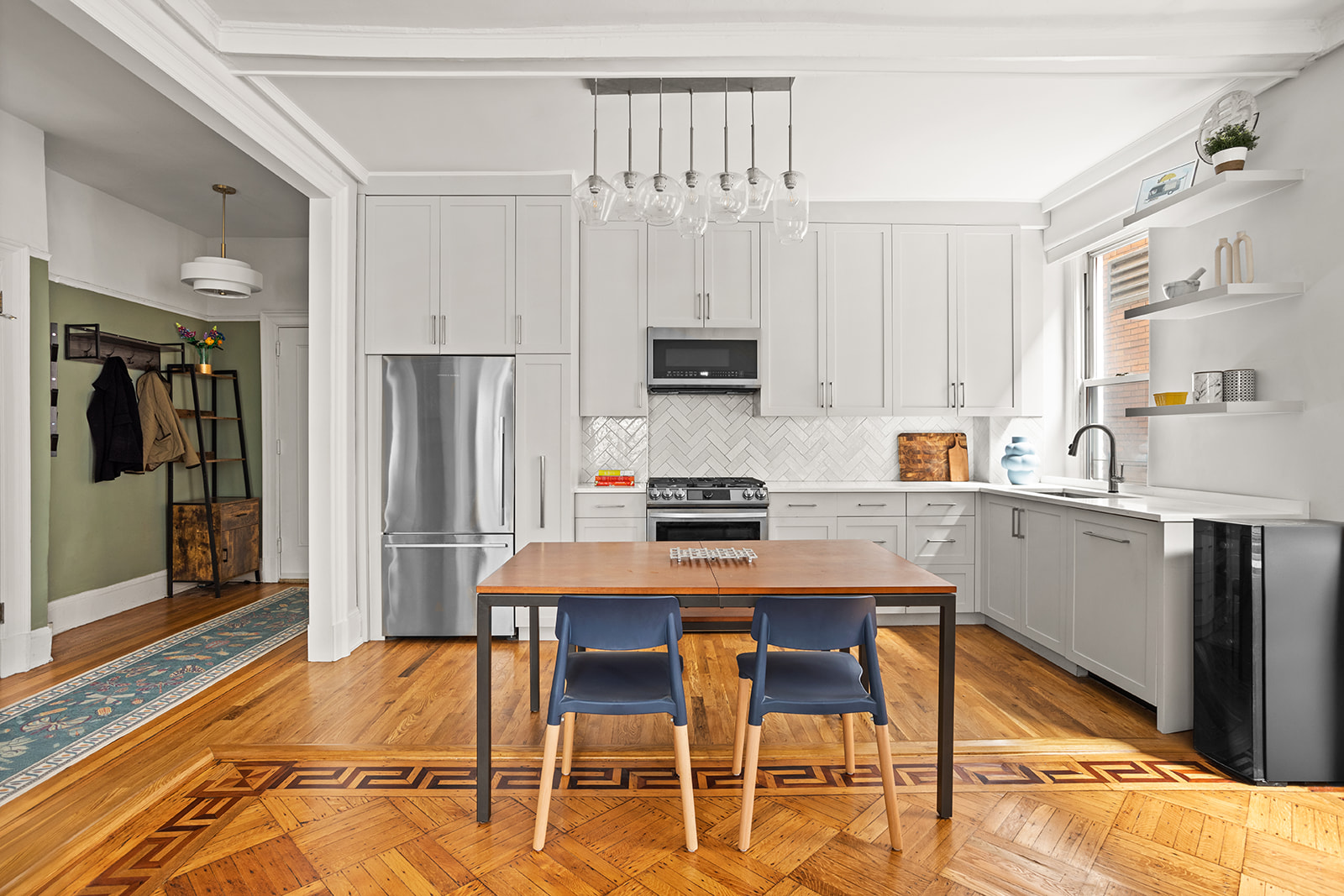 a kitchen with stainless steel appliances a dining table chairs refrigerator and sink