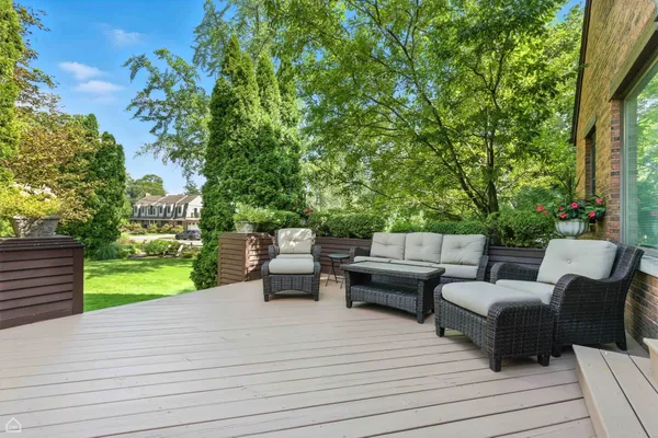 a view of a patio with couches and a table and chairs with wooden floor and fence