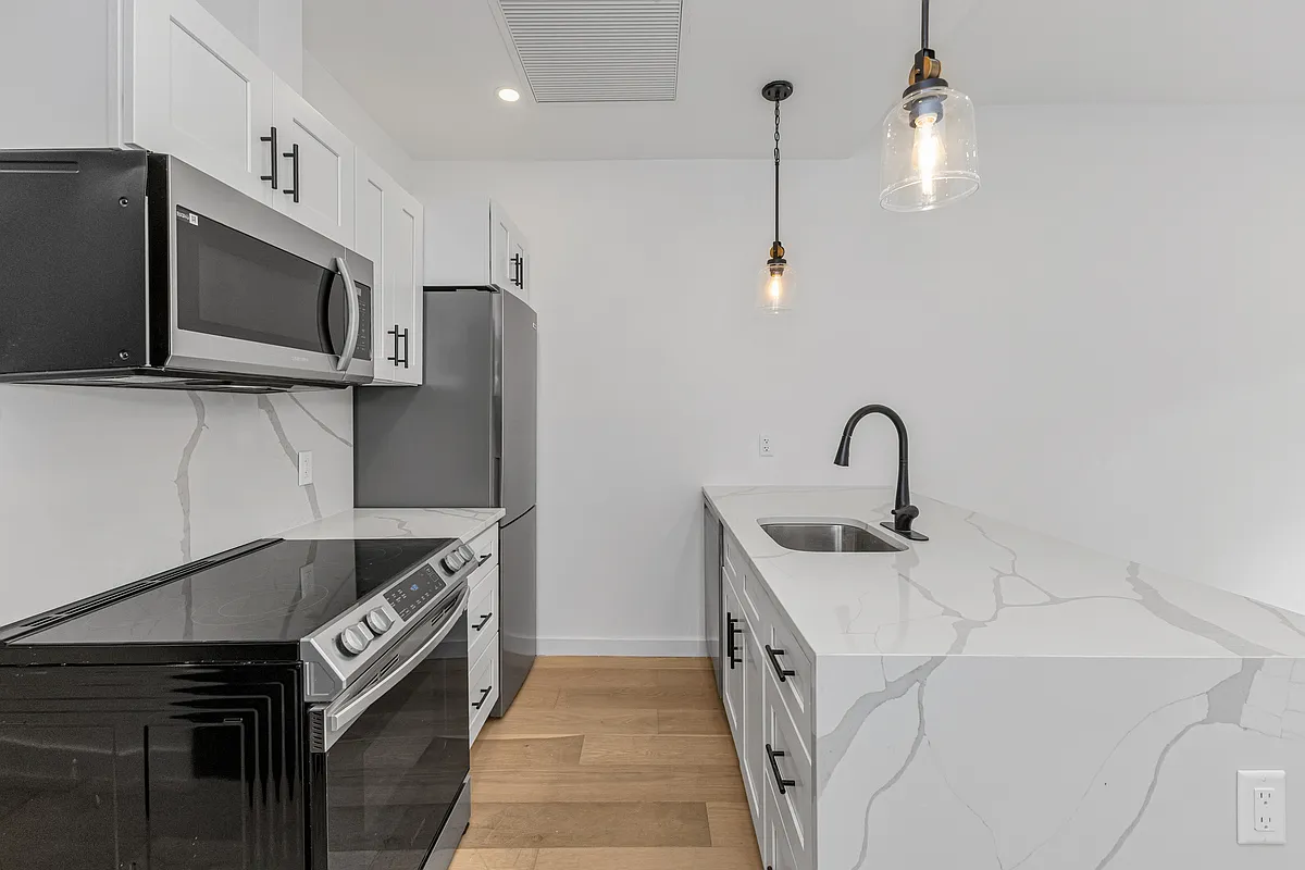 21-10 30th Avenue, Unit 1R Queens, NY 11102 - Photo 3 of 16 a kitchen with stainless steel appliances granite countertop a sink and a microwave