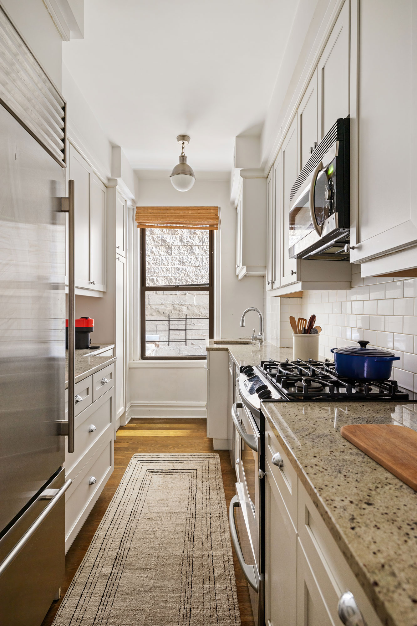 129 East 82nd Street, Unit 1C Manhattan, NY 10028 - Photo 5 of 13 a kitchen with stainless steel appliances granite countertop a stove a sink and a microwave