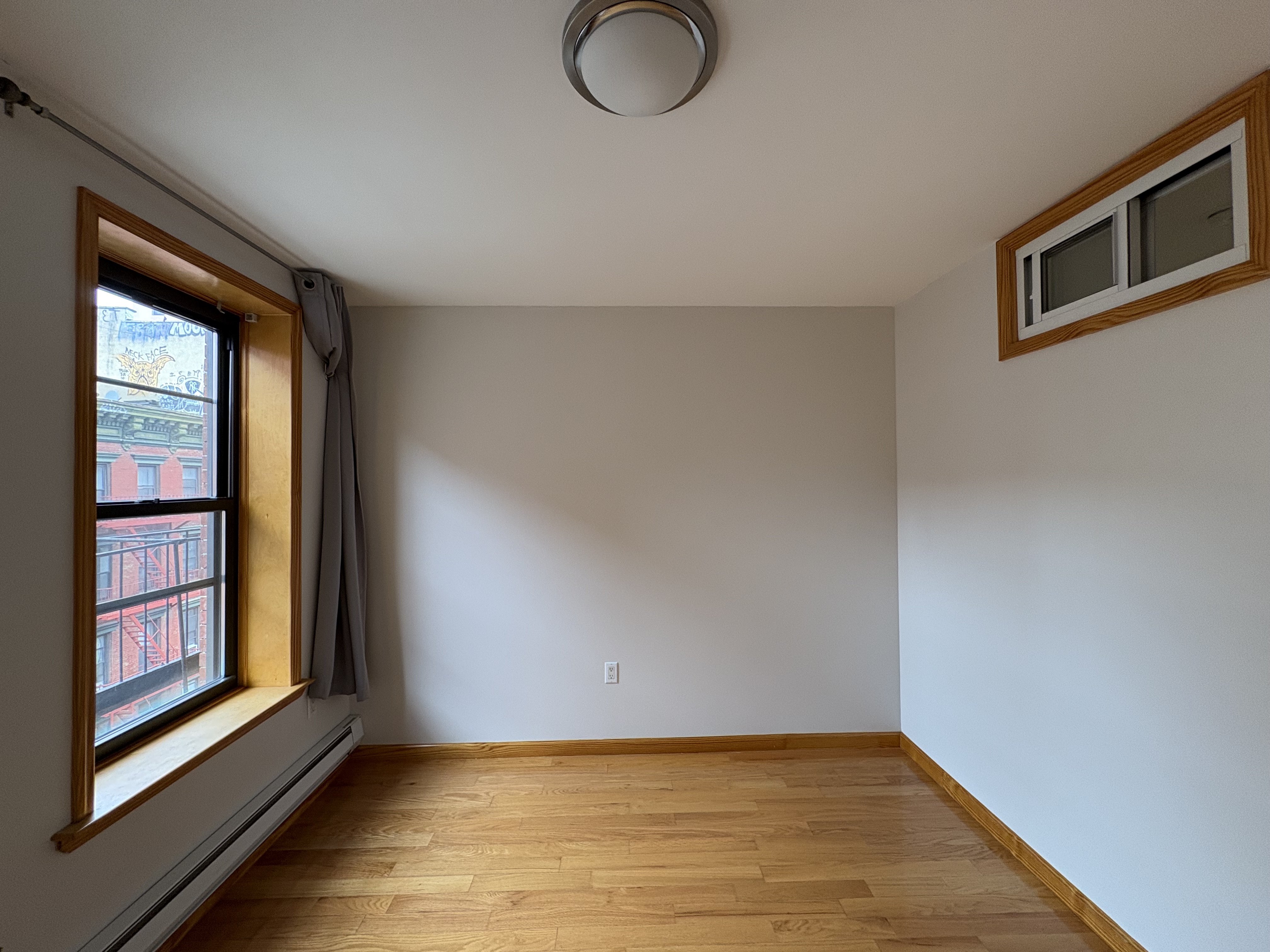 38 Ludlow Street, Unit 15 Manhattan, NY 10002 - Photo 2 of 16 a view of an empty room with wooden floor and a window