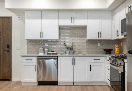 a kitchen with stainless steel appliances granite countertop a stove a sink and white cabinets