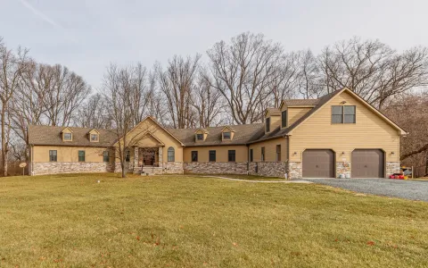 a view of a white house with a big yard and large trees
