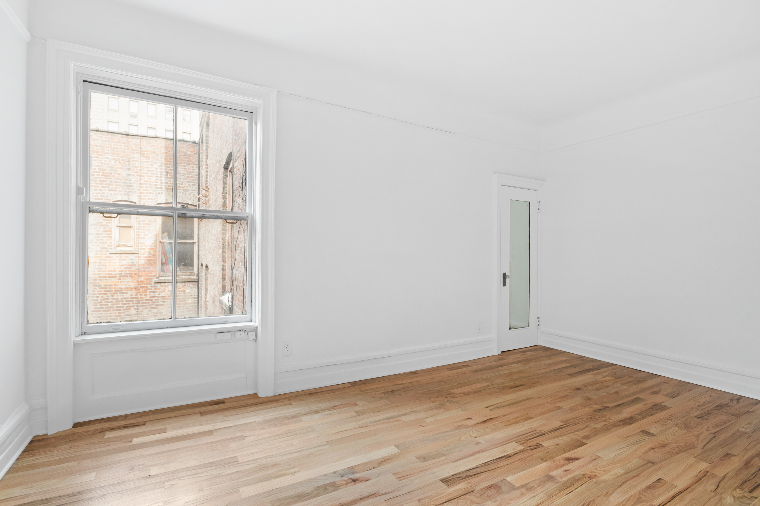50 East 96th Street, Unit 6D Manhattan, NY 10128 - Photo 5 of 7 an empty room with wooden floor and windows