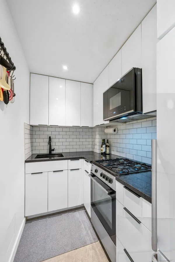 a kitchen with granite countertop a sink dishwasher stove and microwave with wooden floor