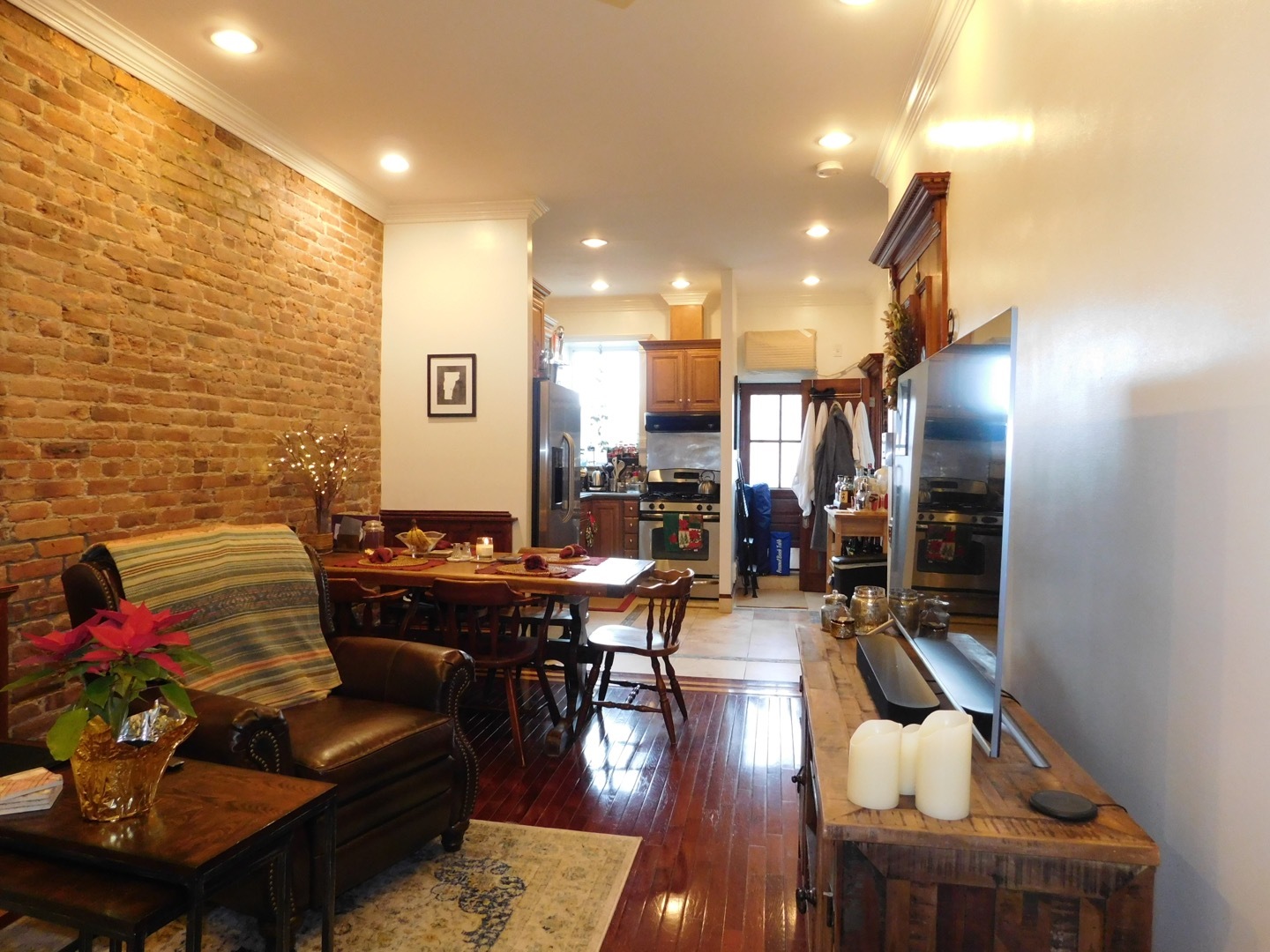 a living room with couches and kitchen view with wooden floor