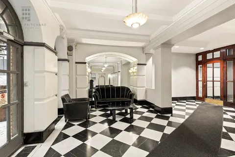 a living room with a black white checkered floor with couches chair and a coffee table