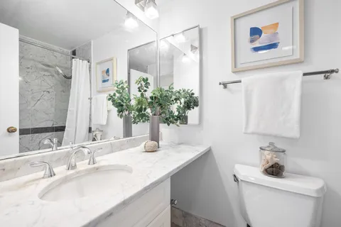 a bathroom with a granite countertop sink a toilet and a mirror