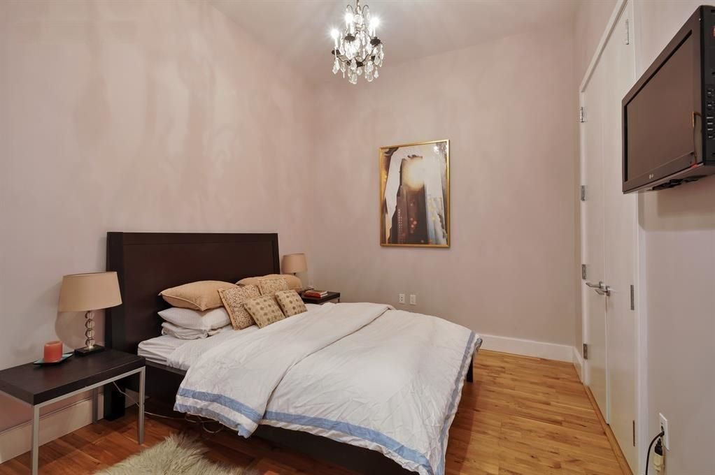 360 Furman Street, Unit 511 Brooklyn, NY 11201 - Photo 6 of 37 a bedroom with a bed wooden floor and lamp