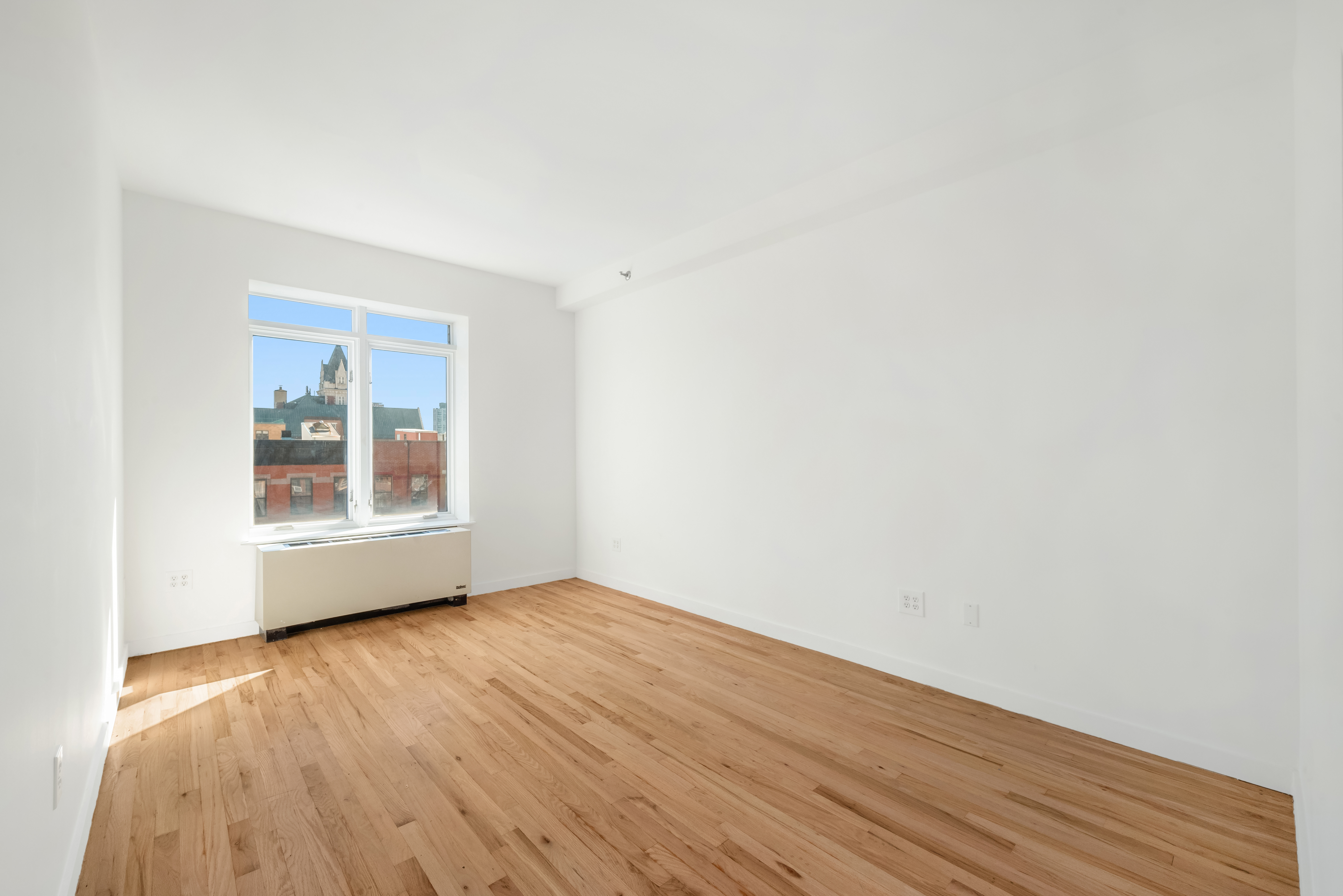 304 West 115th Street, Unit 6A Manhattan, NY 10026 - Photo 8 of 14 a view of an empty room with wooden floor and a window