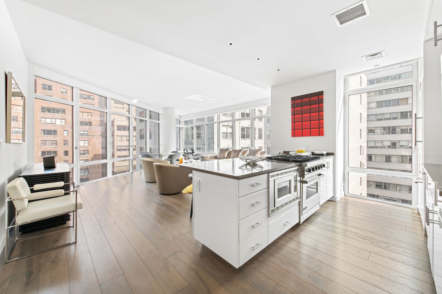 207 East 57th Street, Unit 12A Manhattan, NY 10022 - Photo 3 of 13 a kitchen with stainless steel appliances a stove a sink and white cabinets with wooden floor