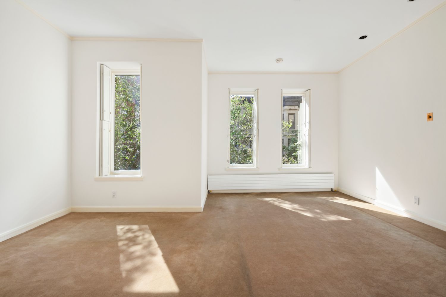 an empty room with windows and fireplace