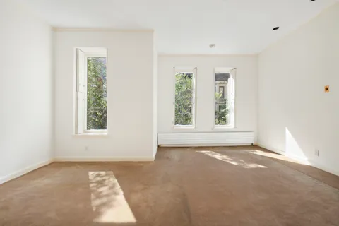 an empty room with windows and fireplace