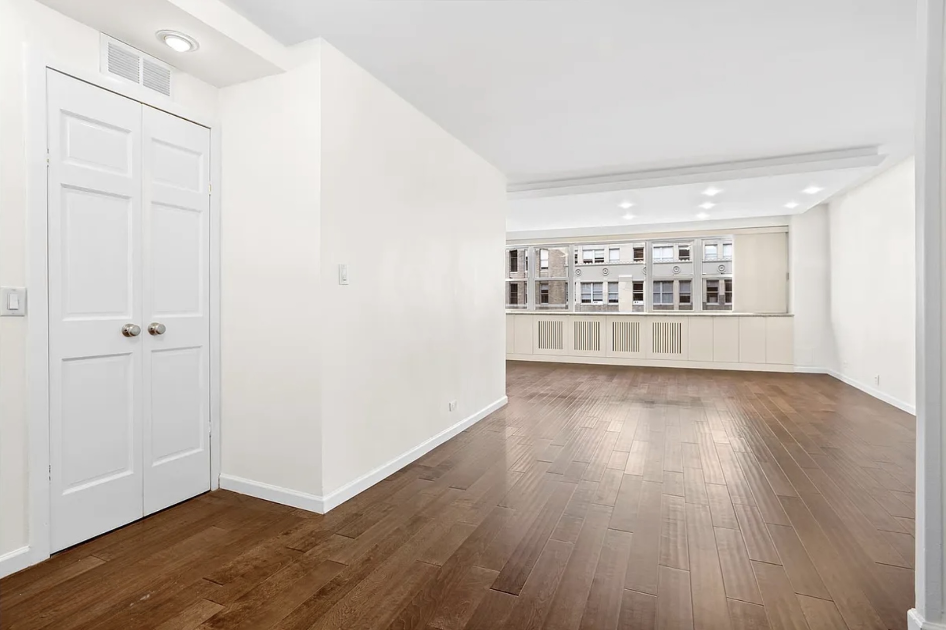an empty room with wooden floor and windows
