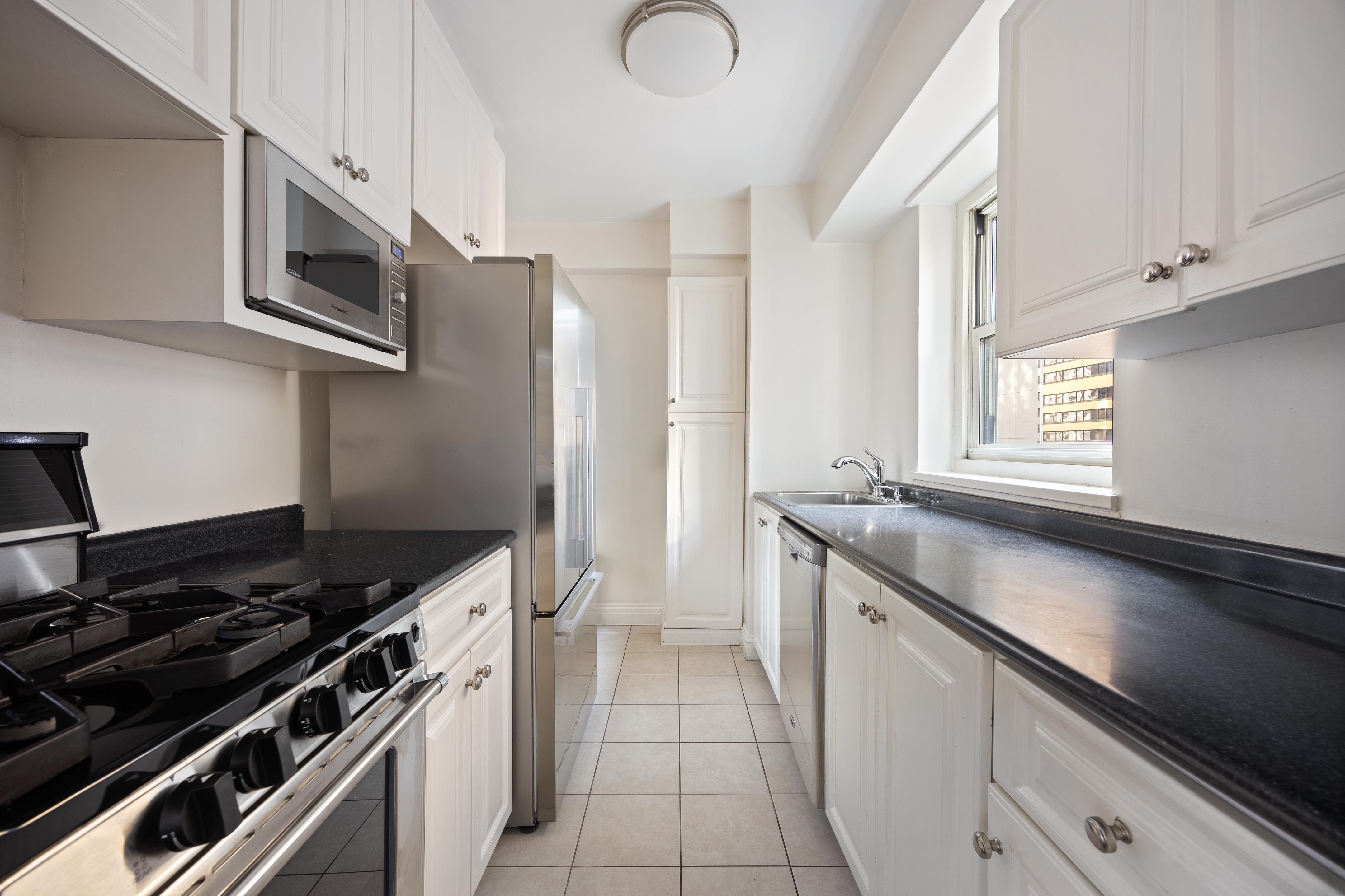 159 West 53rd Street, Unit 16E Manhattan, NY 10019 - Photo 3 of 10 a kitchen with stainless steel appliances granite countertop a stove and a microwave