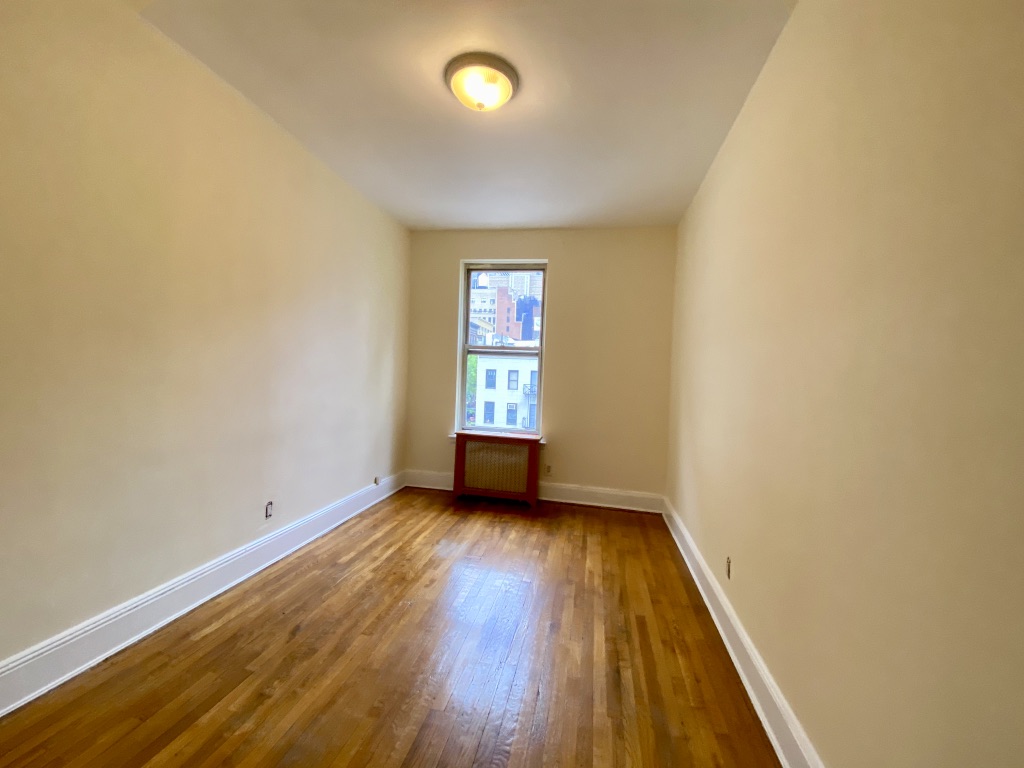 619 9th Avenue, Unit 3E Manhattan, NY 10036 - Photo 8 of 22 an empty room with wooden floor and windows