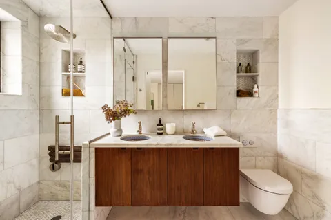 a bathroom with a granite countertop sink toilet and mirror