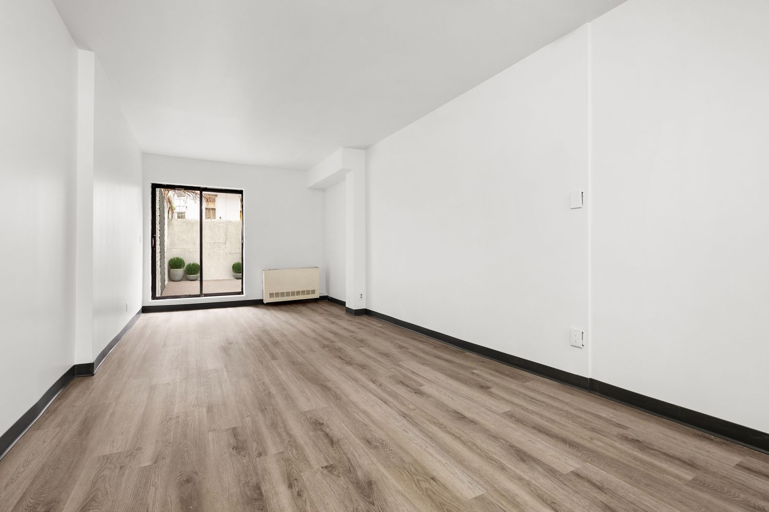 343 East 76th Street, Unit BA Manhattan, NY 10021 - Photo 1 of 7 an empty room with wooden floor and windows