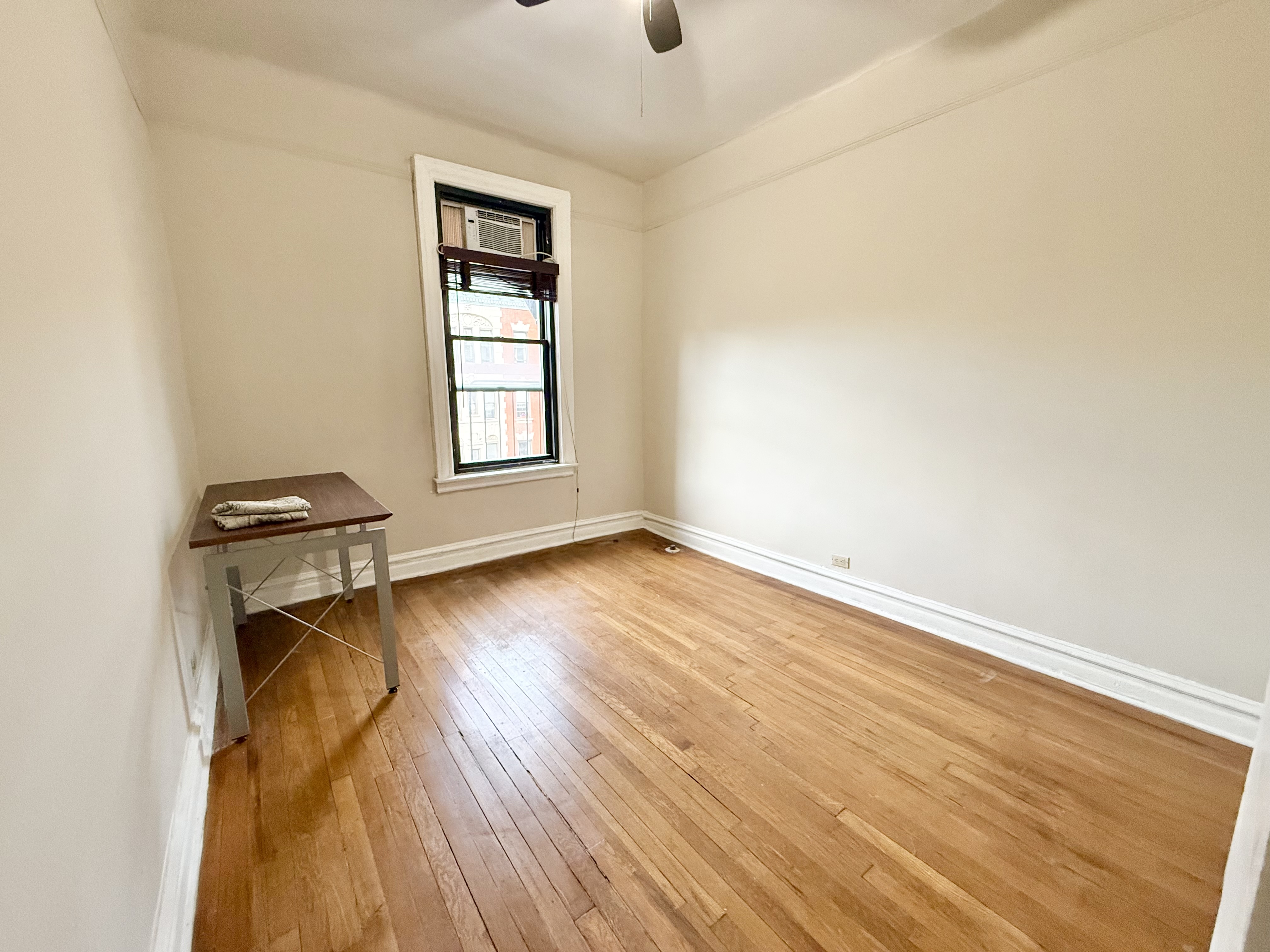 170 Claremont Avenue, Unit 19 Manhattan, NY 10027 - Photo 6 of 9 an empty room with wooden floor and windows